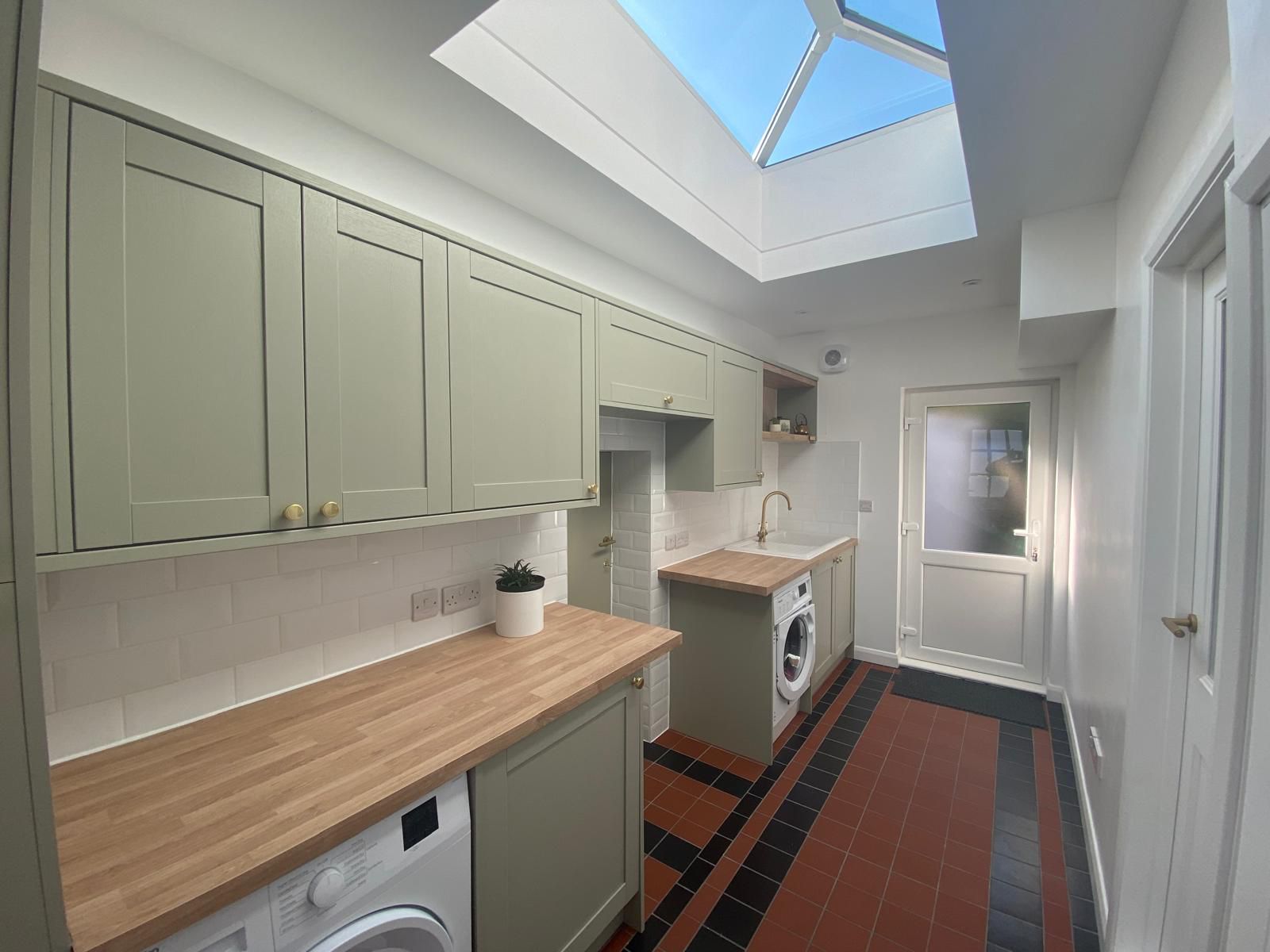 Completed Northampton utility room with green cabinets and quarry tile floor